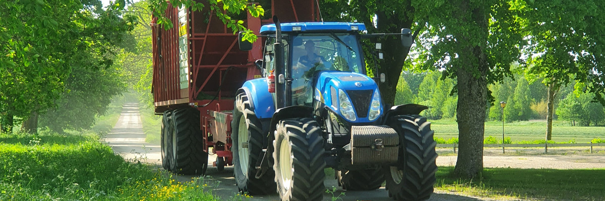 Traktor med hackvagn i en allé