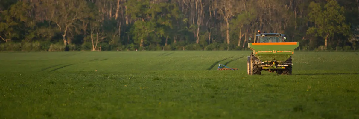 Traktor som sprider mineralgödsel på ett fält.