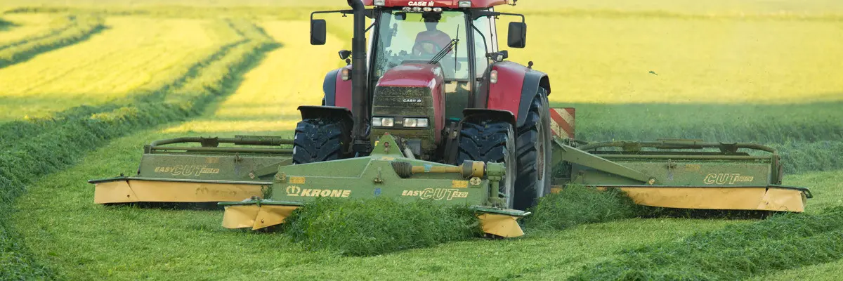 Traktor slår gräs med slåtterkross 